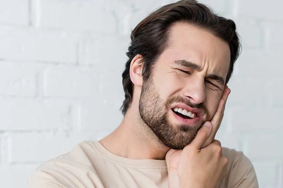 Male patient holding his cheek in pain before receiving emergency dental treatment in Las Vegas. 