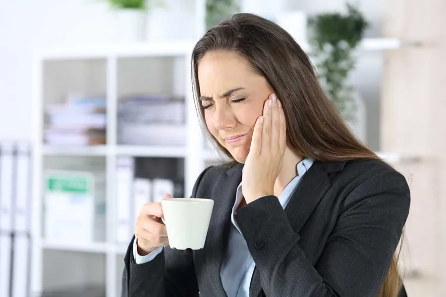 Woman dressed in executive suit holding her face in noticeable pain resulting from TMJ in Las Vegas. 